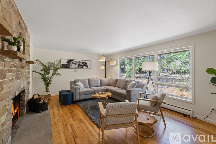 A living room with a fireplace and a grey couch.