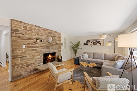 A living room with a stone fireplace and a grey couch.