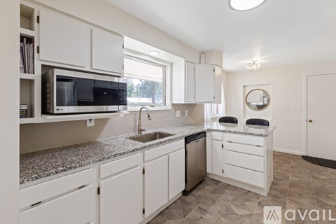 A kitchen with white cabinets and a granite countertop.