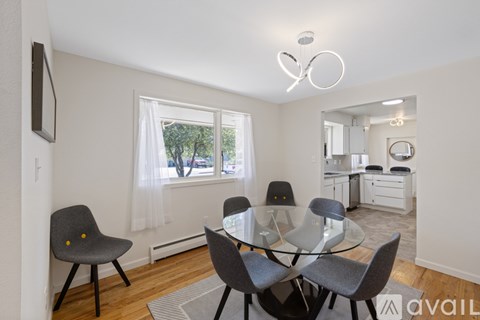 A modern dining room with a glass table and grey chairs.