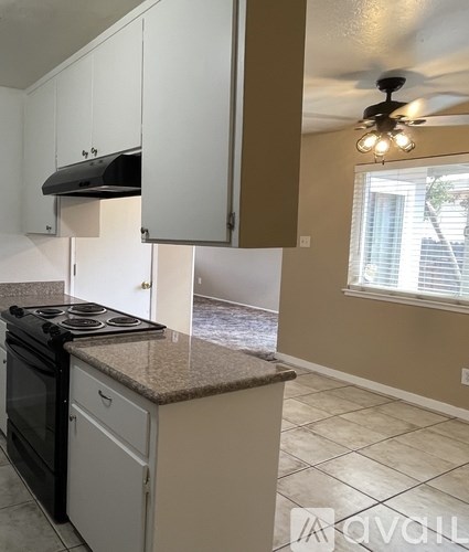 A kitchen with a black stove top oven and white cabinets.