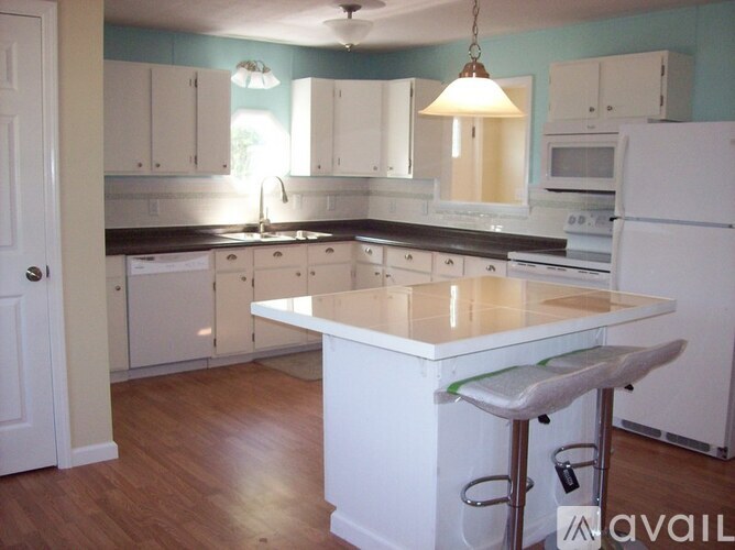 A kitchen with white cabinets and a white island.