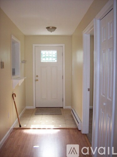 A hallway with a white door and a wooden floor.
