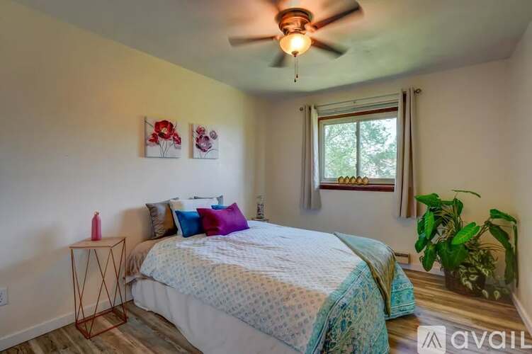 A bedroom with a bed, pillows, a ceiling fan, and a window.