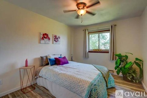 A bedroom with a bed, pillows, a ceiling fan, and a window.