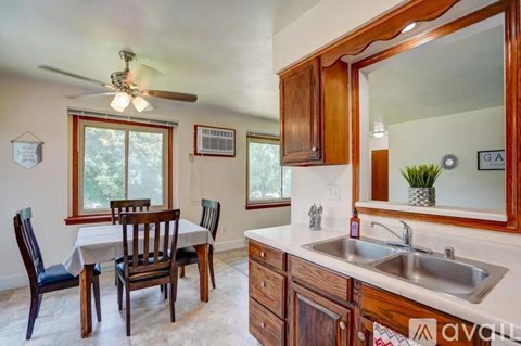 A kitchen with a table and chairs and a ceiling fan.
