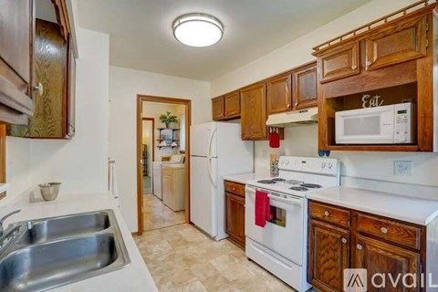 A kitchen with wooden cabinets and a white stove top oven.