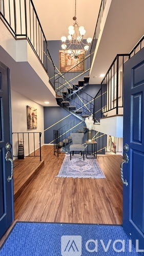 A hallway with a staircase and a chandelier.