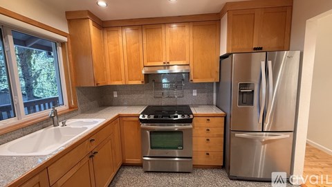 A kitchen with wooden cabinets and stainless steel appliances is available for rent.