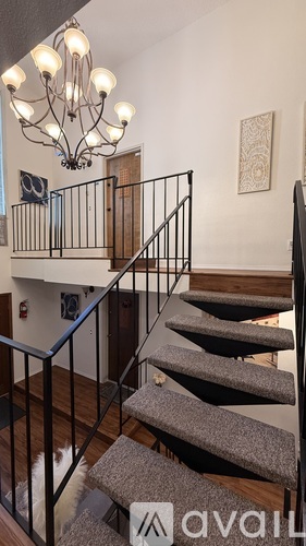A staircase with a metal railing and a chandelier hanging from the ceiling.