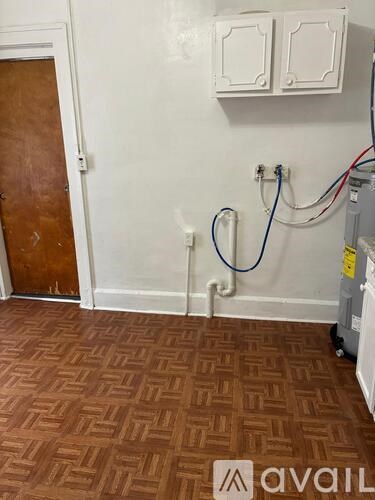 A room with a brown floor and a white wall with a door and a cabinet.