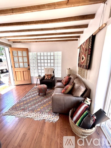 A living room with a brown leather couch and a woven basket on the floor.
