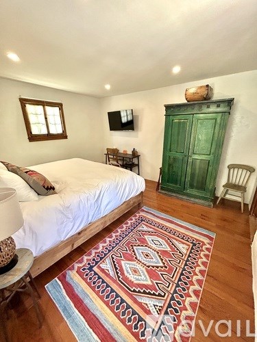 A bedroom with a bed, a rug, a chair, and a green door.