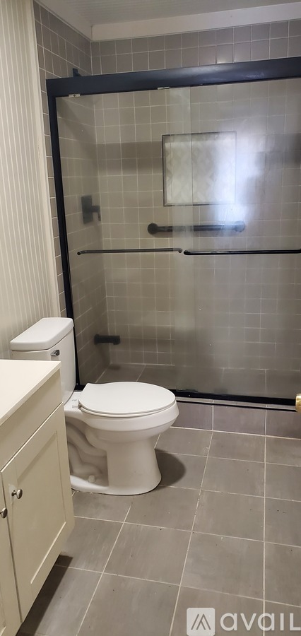 A white toilet in a small bathroom with a glass shower door.
