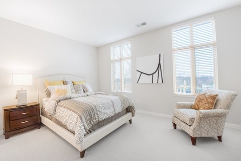 A bedroom with a large bed and a chair.