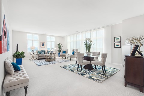 A living room with a white sofa, a coffee table, and a dining table with chairs.
