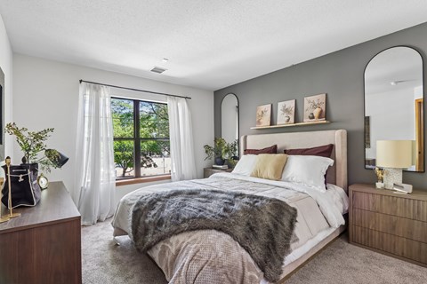 A bedroom with a large bed and a window with curtains.