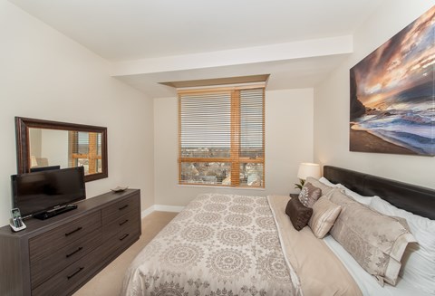 A bedroom with a large bed, a television, and a painting on the wall.