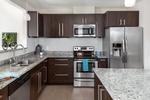 A kitchen with a granite counter top and stainless steel appliances.