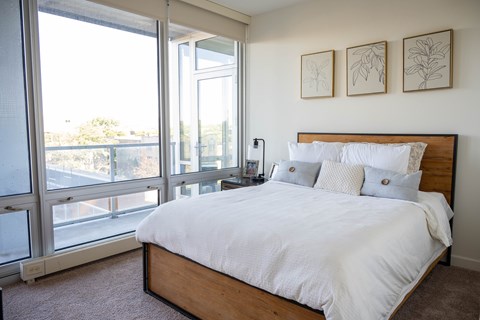 A bedroom with a large bed and a balcony with sliding doors.