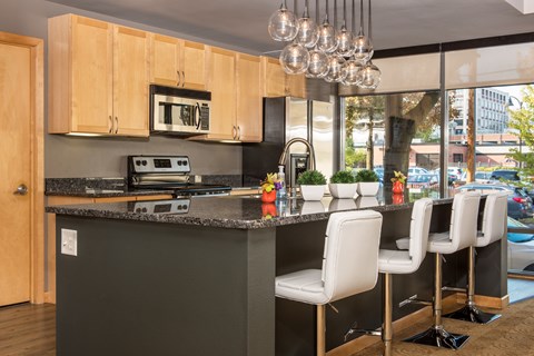 A kitchen with a black countertop and white chairs.