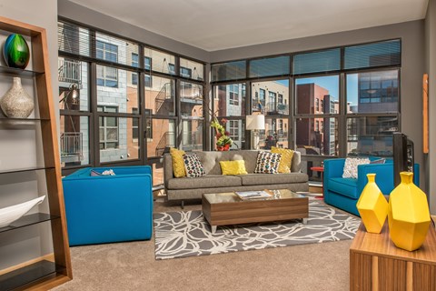 A living room with a grey couch and a blue ottoman.