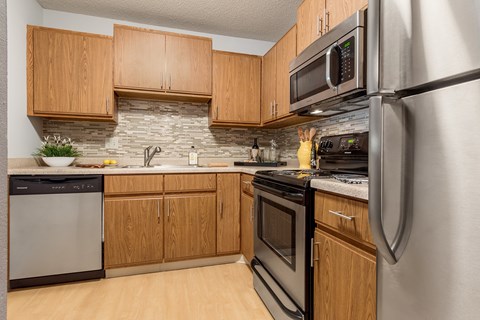 A kitchen with wooden cabinets and a stone backsplash.