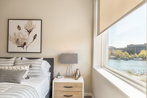 A bedroom with a bed, nightstand, and a framed picture of flowers on the wall.