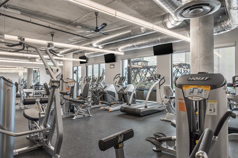 A gym with a variety of equipment including treadmills, weights, and exercise machines.