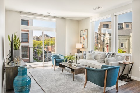 A blue vase sits on a table in a living room with a couch and a chair.