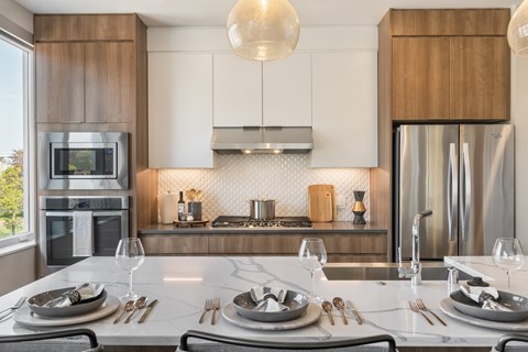 A modern kitchen with a dining table set for two.