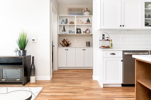 A kitchen with white cabinets and a wooden floor.