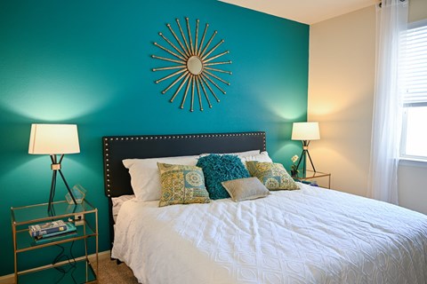 A bedroom with a white bed and a blue wall.