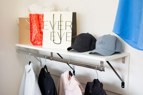 A white shelf with clothes and a bag that says "EVER EVE".