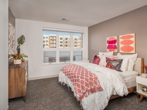 A bedroom with a large bed and a window overlooking a cityscape.
