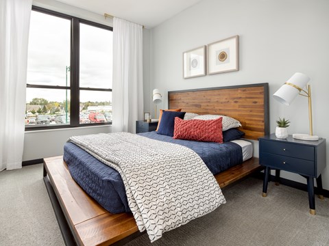 A bedroom with a large bed and a window overlooking a parking lot.