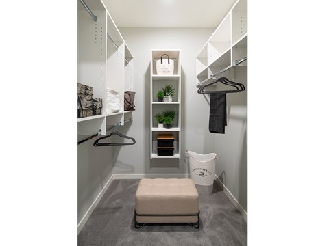 A small closet with a bench and a hanging space.