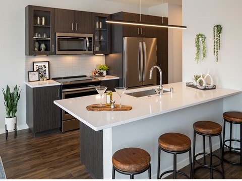 A modern kitchen with dark brown cabinets and white countertops.