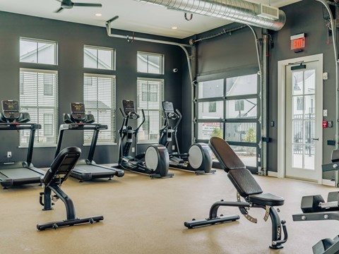 A gym with treadmills, elliptical machines, and a weight bench.
