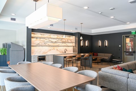 A modern dining area with a long wooden table surrounded by grey chairs.