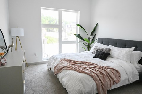 A bedroom with a large bed and a window overlooking a balcony.