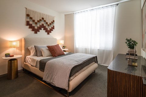 A bedroom with a large bed and a small table with a plant on it.
