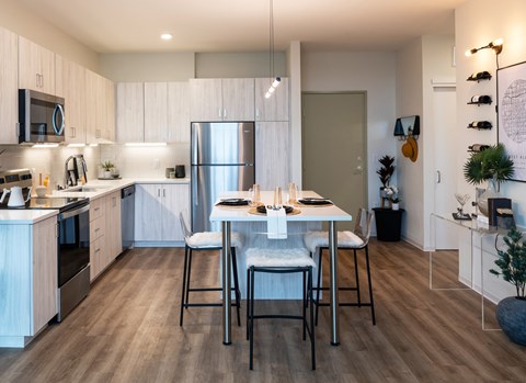 A modern kitchen with a dining table set for two.
