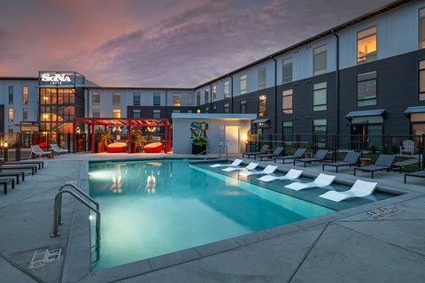 A pool area with a slide and lounge chairs outside a building.