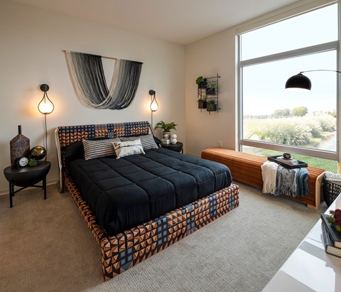 A bedroom with a large bed and a window overlooking a field.