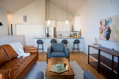 A brown leather couch sits in a living room with a grey armchair and a coffee table.