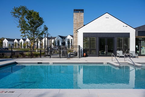 A swimming pool in front of a white building with a black fence around it.