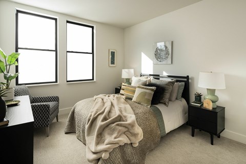 A bedroom with a bed, nightstand, and chair.
