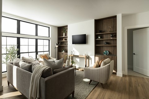 A modern living room with a grey sofa and a television on the wall.