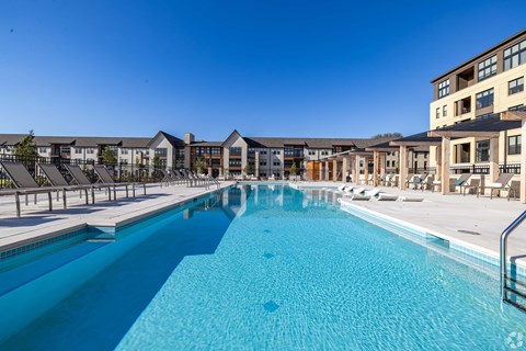 A large swimming pool in front of a building with a clear blue sky.